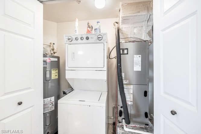 Utility room with water heater and stacked washer / drying machine