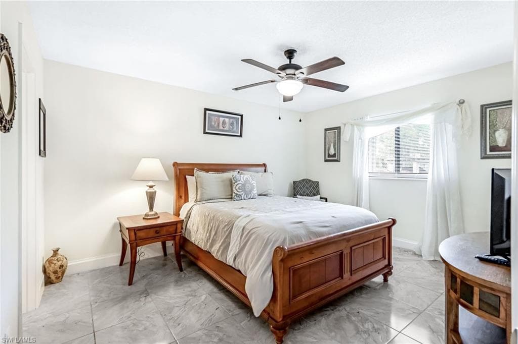 Bedroom with ceiling fan and light tile patterned floors