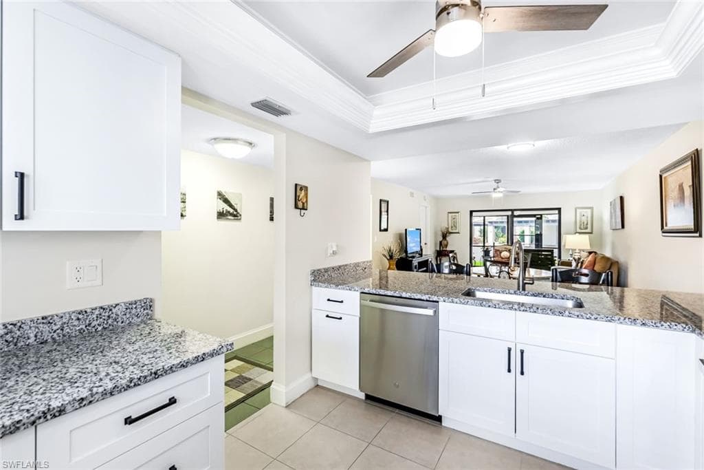 Kitchen with ceiling fan, white cabinets, dishwasher, and light tile patterned floors