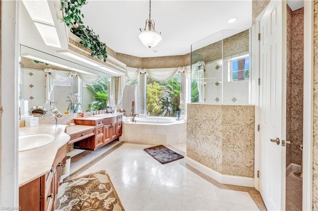 Bathroom with tile patterned floors, a skylight, independent shower and bath, and vanity