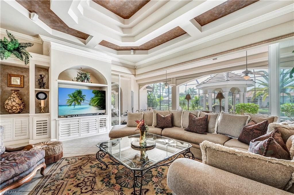 Living room with ornamental molding, a tray ceiling, ceiling fan, and tile patterned flooring