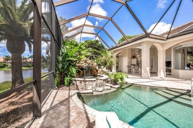 View of swimming pool featuring a water view, a lanai, and a patio