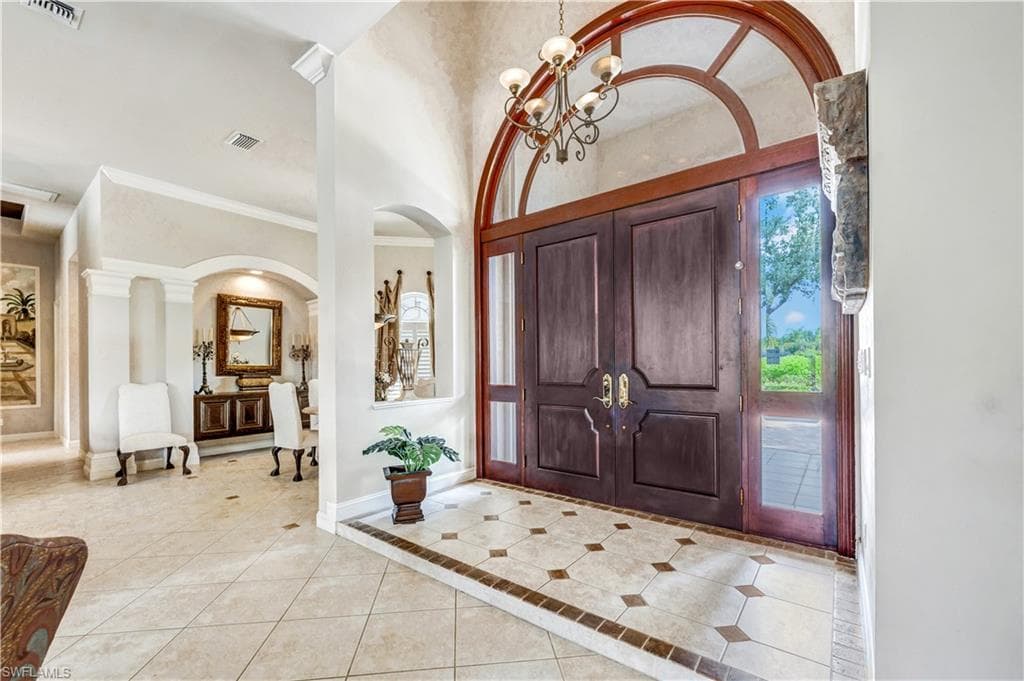 Tiled entrance foyer featuring an inviting chandelier and crown molding