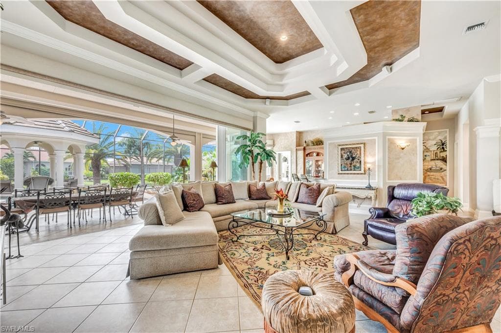Living room featuring crown molding, a raised ceiling, and light tile patterned flooring