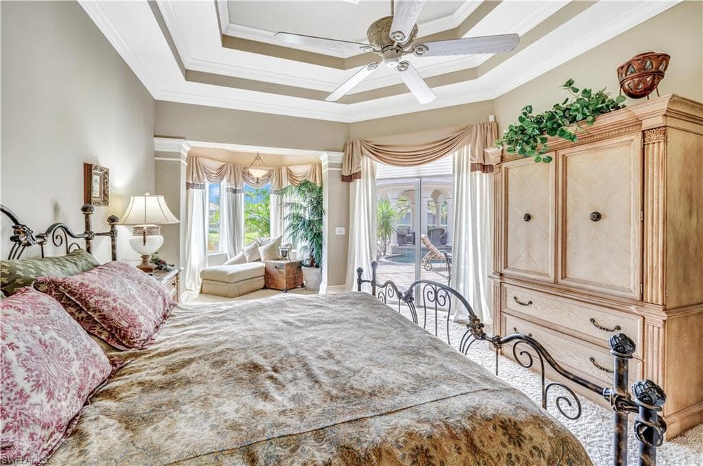 Bedroom with ceiling fan, a raised ceiling, access to exterior, and ornamental molding