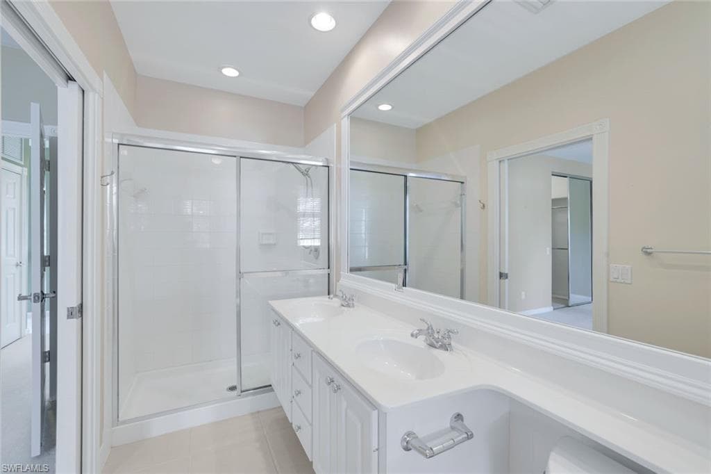 Bathroom featuring vanity, tile patterned flooring, and a shower with door