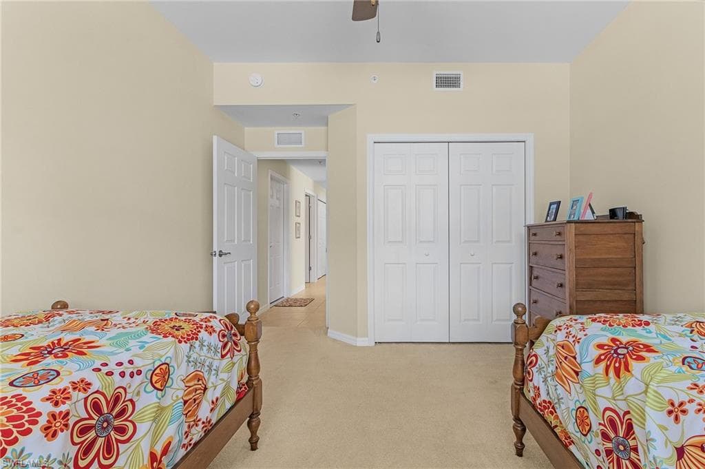 Bedroom featuring light colored carpet, ceiling fan, and a closet