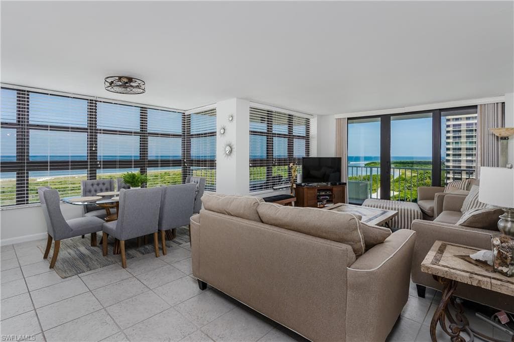 Living room featuring a wall of windows, radiator heating unit, and light tile patterned floors