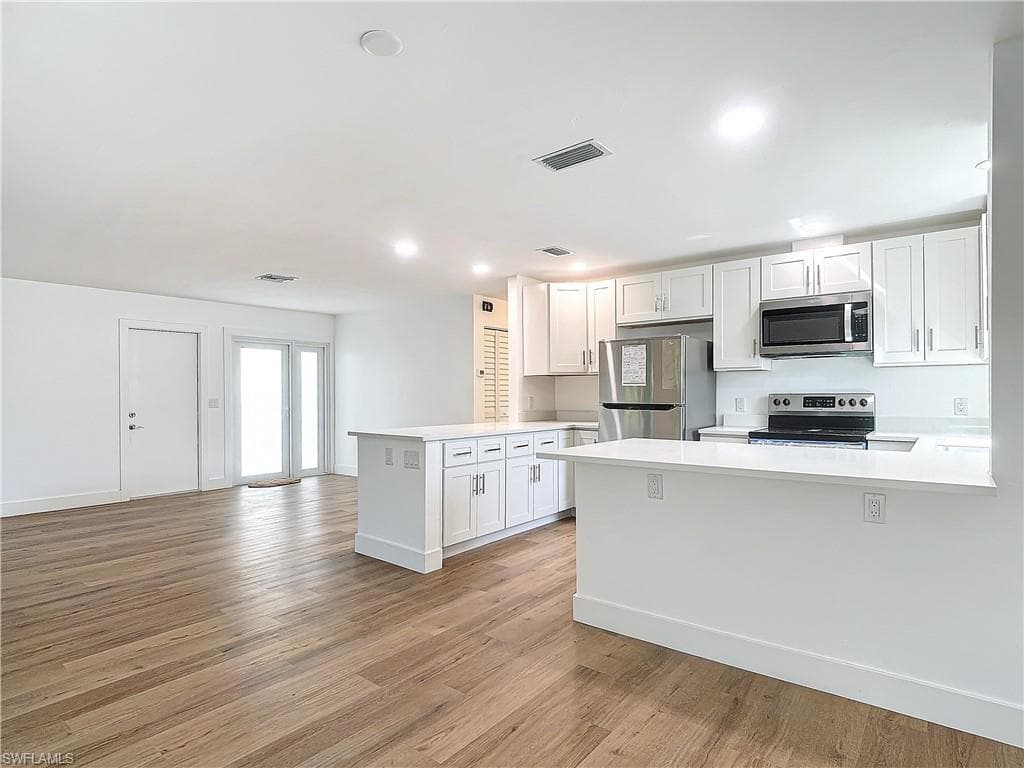 Kitchen with kitchen peninsula, white cabinetry, and stainless steel appliances