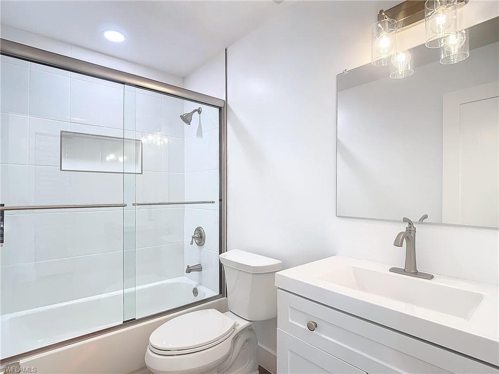 Full bathroom featuring enclosed tub / shower combo, vanity, and toilet