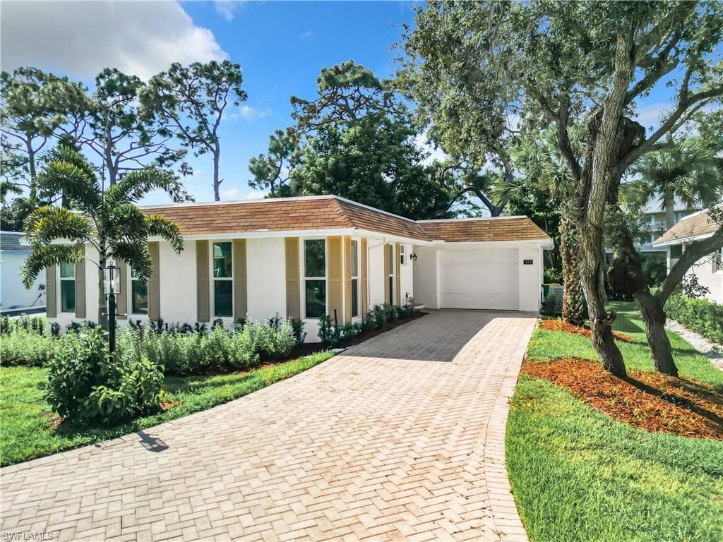 View of front facade featuring a front yard and a garage