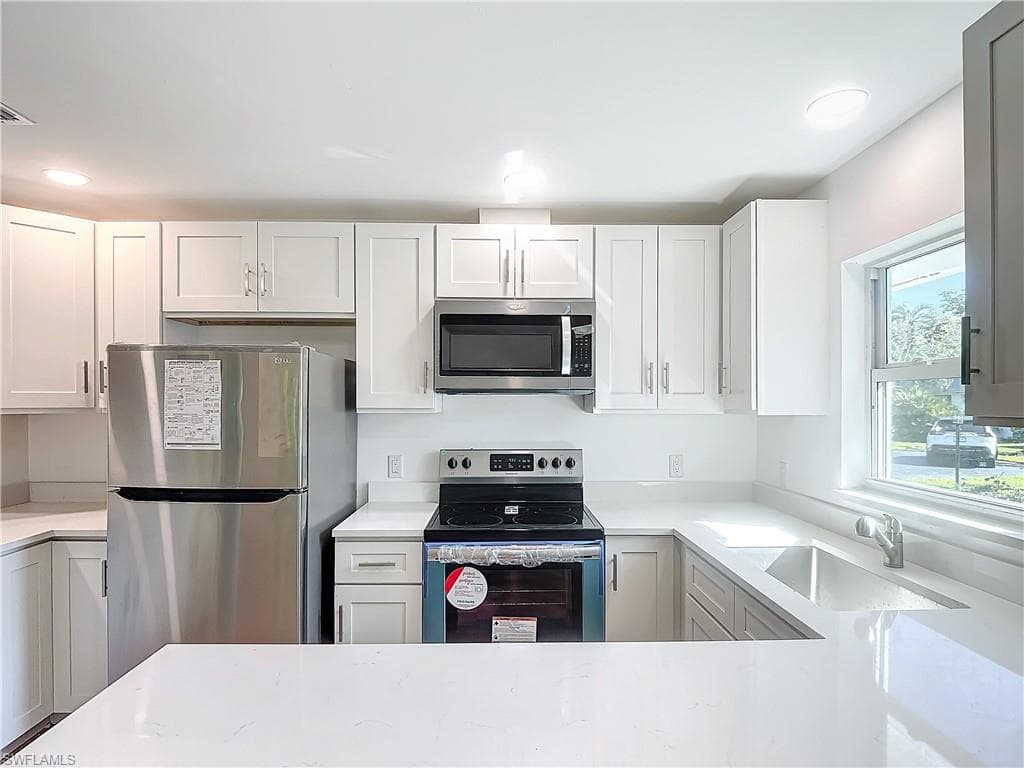 Kitchen featuring stainless steel appliances, sink, and white cabinetry