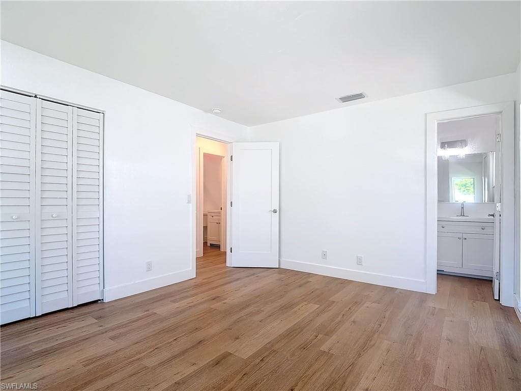 Unfurnished bedroom featuring light hardwood / wood-style flooring, ensuite bath, and sink