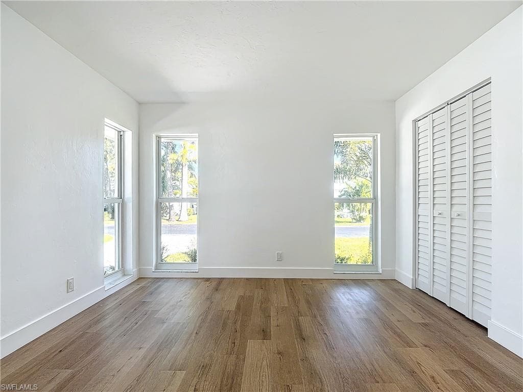 Unfurnished bedroom with light hardwood / wood-style floors and multiple windows