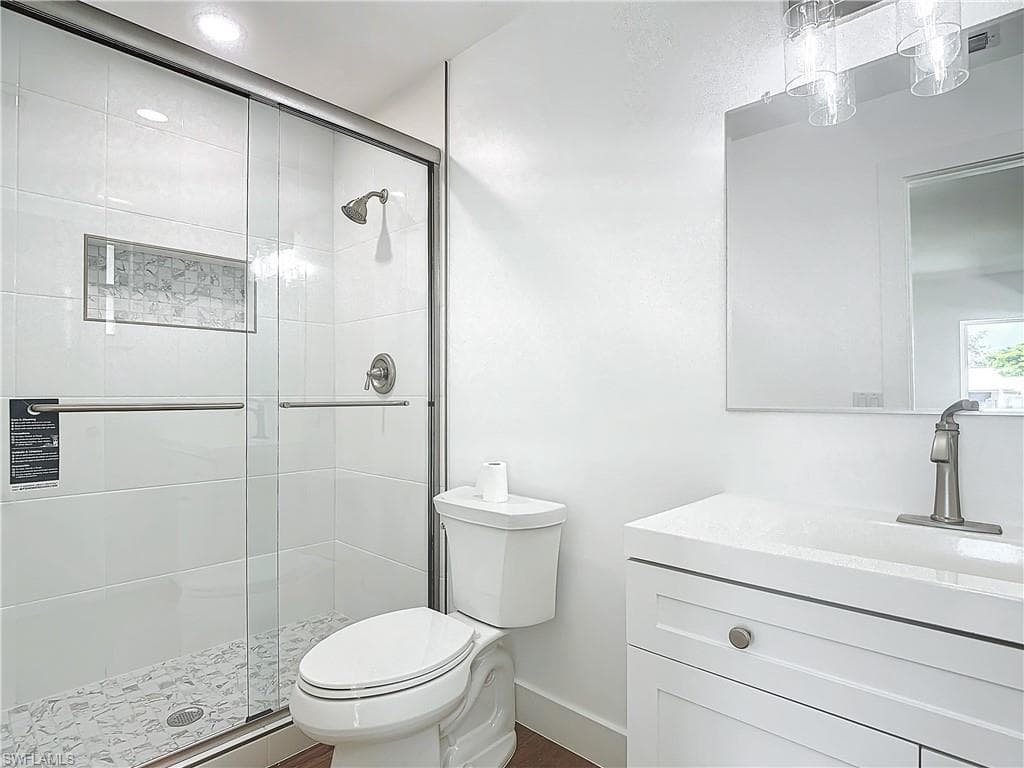 Bathroom featuring a shower with door, vanity, and toilet