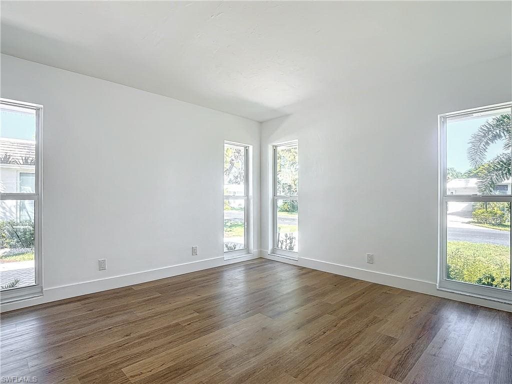 Unfurnished room featuring dark hardwood / wood-style floors and a wealth of natural light