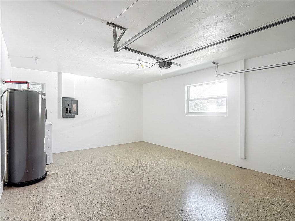 Garage featuring water heater, a garage door opener, and electric panel