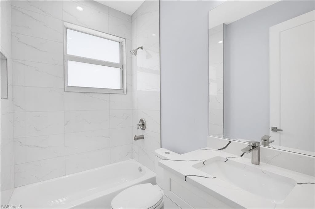 Full bathroom featuring tiled shower / bath combo, vanity, and toilet