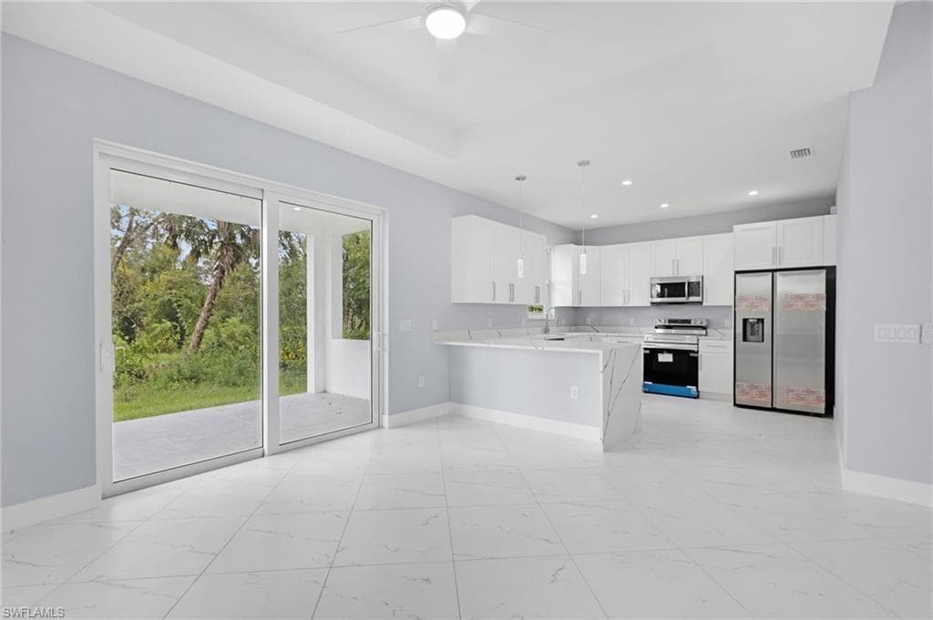 Kitchen featuring pendant lighting, white cabinetry, kitchen peninsula, appliances with stainless steel finishes, and ceiling fan
