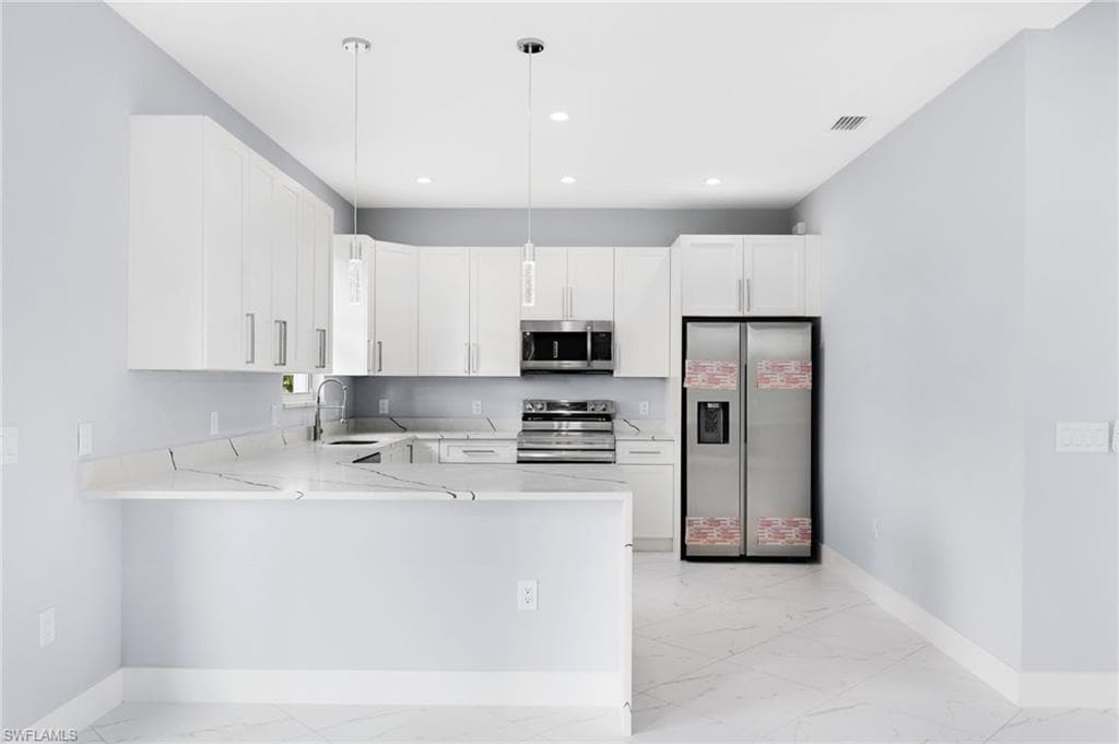 Kitchen featuring hanging light fixtures, kitchen peninsula, stainless steel appliances, and white cabinets