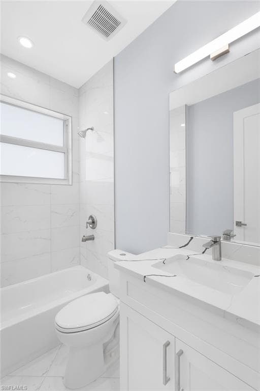 Full bathroom featuring tiled shower / bath combo, vanity, and toilet