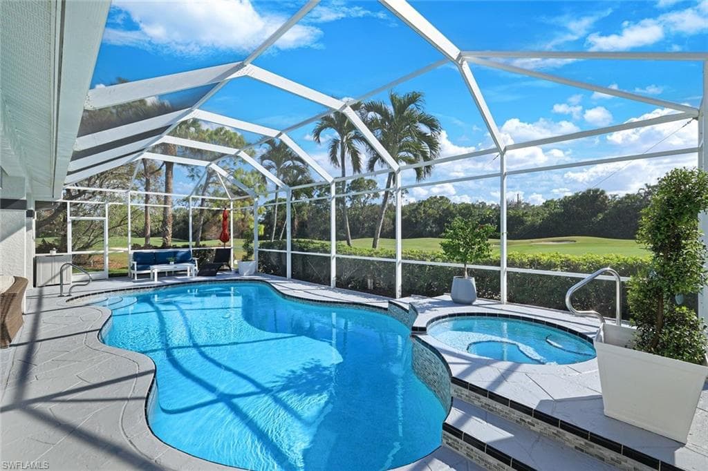 View of pool featuring an in ground hot tub, a patio area, and glass enclosure