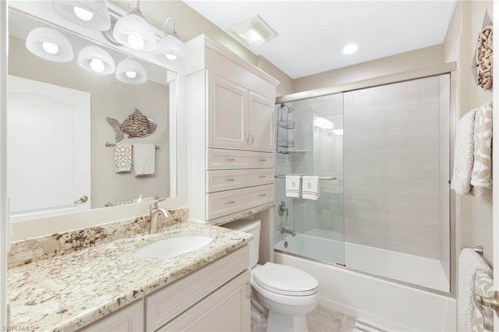 Full bathroom with toilet, enclosed tub / shower combo, and vanity