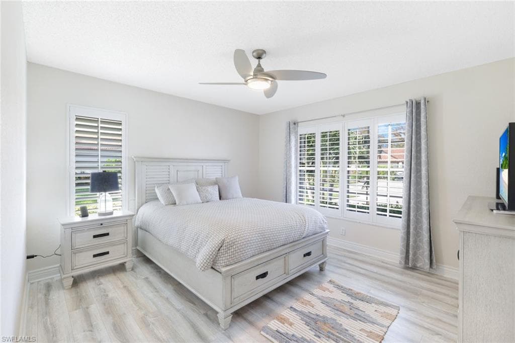 Bedroom featuring light hardwood / wood-style flooring, ceiling fan, and multiple windows