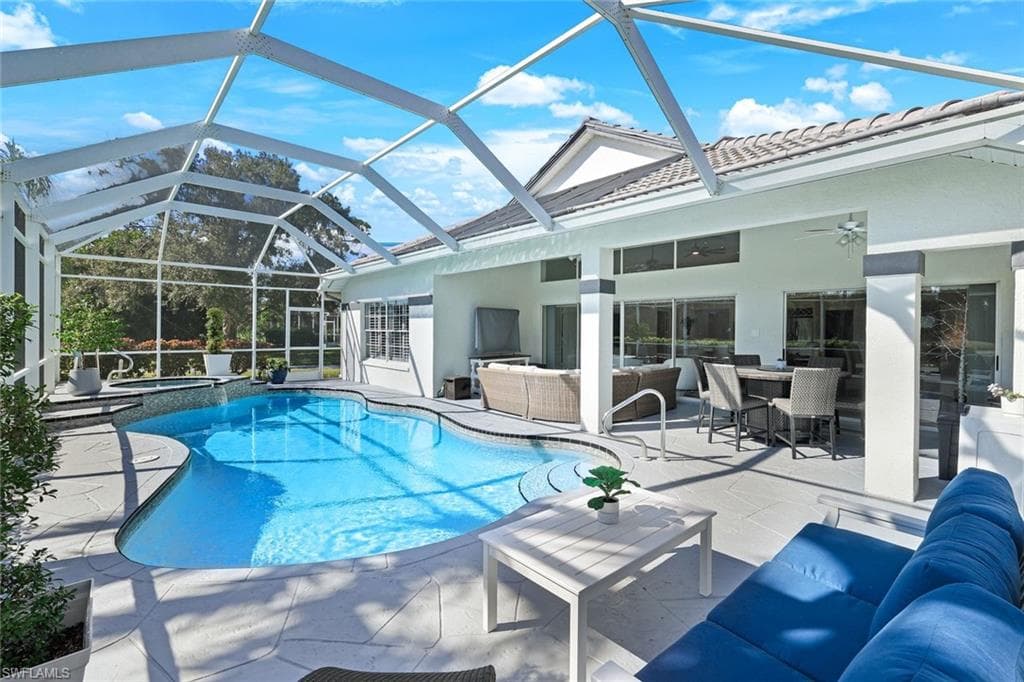 View of pool featuring an in ground hot tub, an outdoor living space, a patio area, and glass enclosure