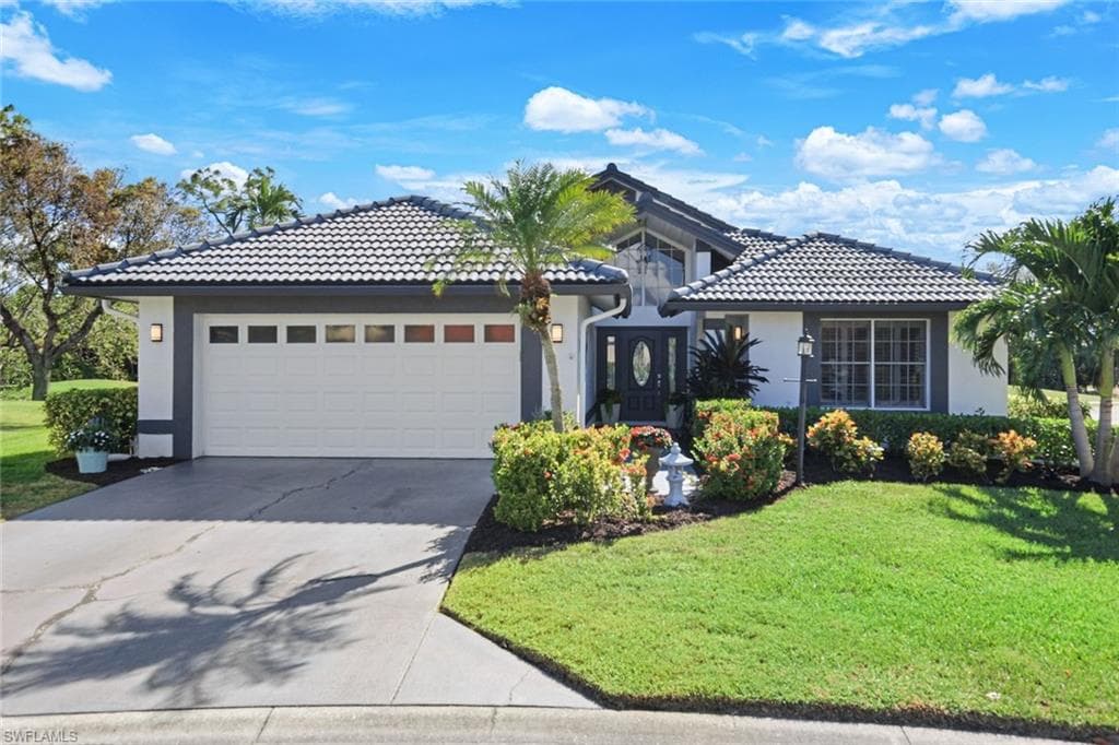 Mediterranean / spanish-style house with a garage and a front lawn