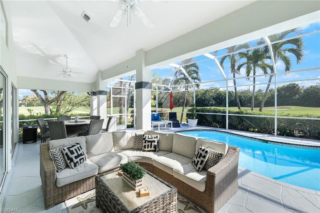 View of swimming pool featuring ceiling fan, glass enclosure, a patio area, and an outdoor hangout area