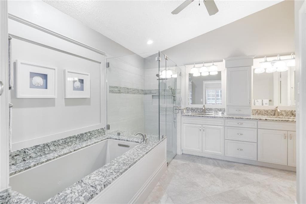Bathroom featuring lofted ceiling, plus walk in shower, vanity, a textured ceiling, and ceiling fan