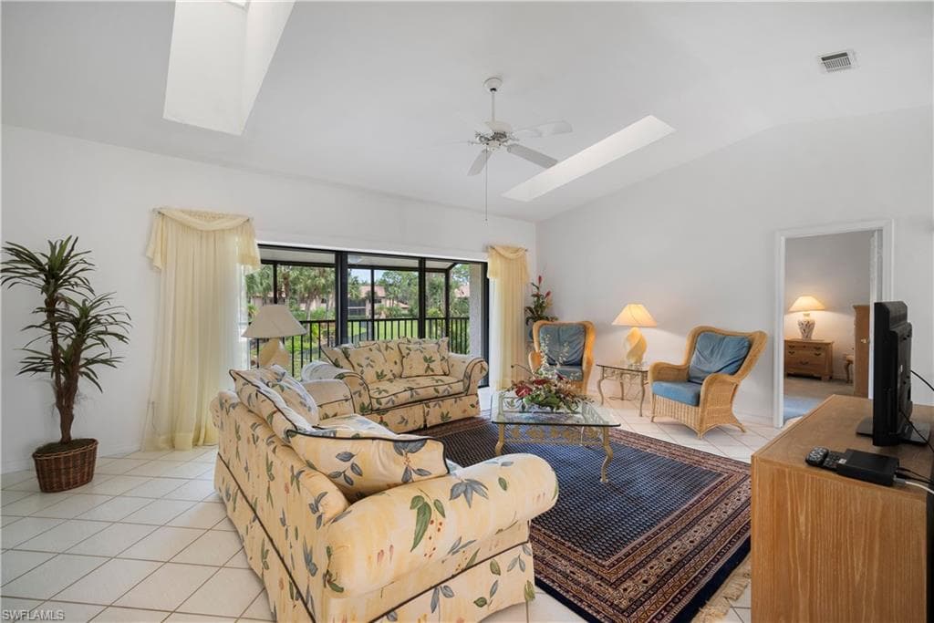 Living room with vaulted ceiling, light tile patterned floors, and ceiling fan