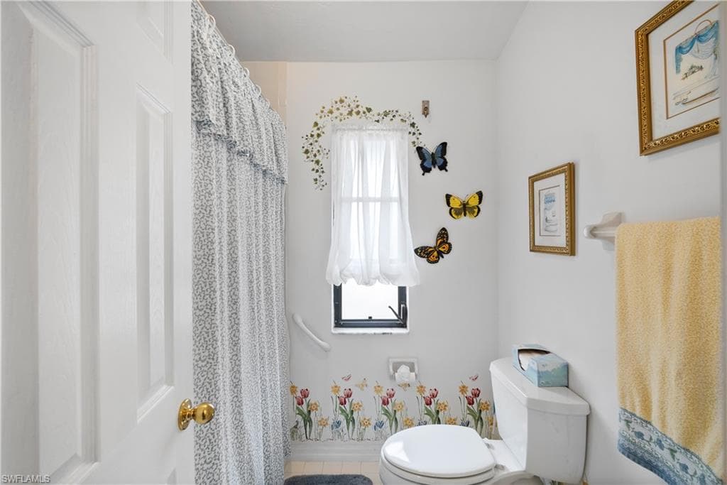Bathroom with toilet, tile patterned floors, and plenty of natural light