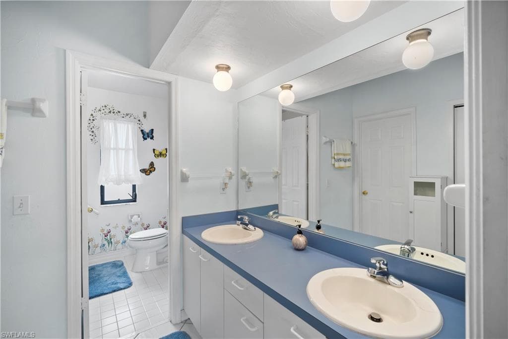Bathroom featuring toilet, vanity, and tile patterned floors