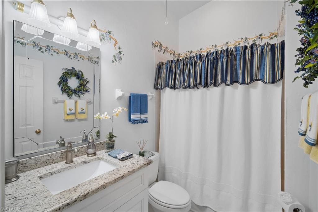 Bathroom featuring toilet, vanity, and a shower with shower curtain