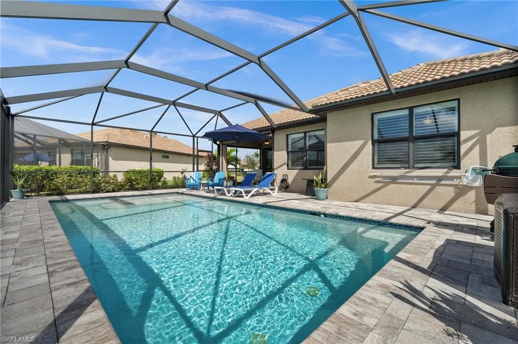 View of swimming pool with glass enclosure and a patio area