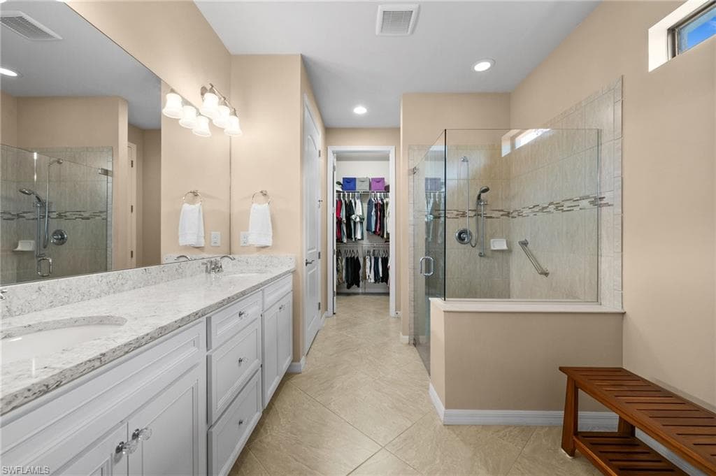 Bathroom featuring tile patterned flooring, vanity, and walk in shower