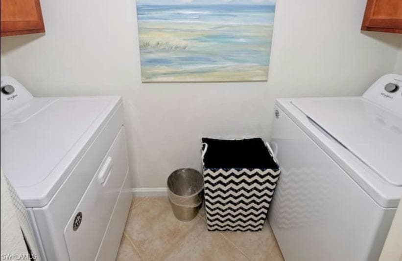 Laundry area with cabinets, light tile patterned flooring, and washing machine and clothes dryer