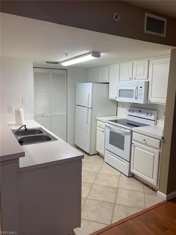 Kitchen with white cabinetry, sink, and white appliances