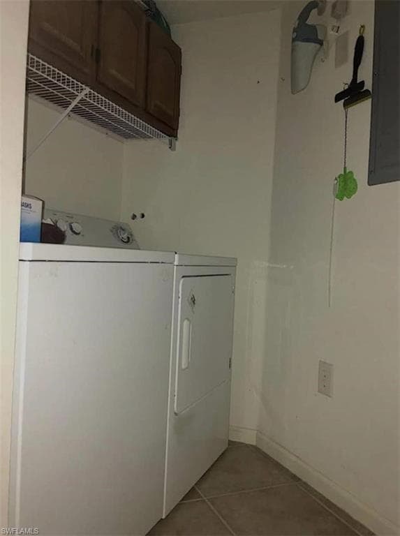 Clothes washing area featuring tile patterned flooring, cabinets, electric panel, and separate washer and dryer