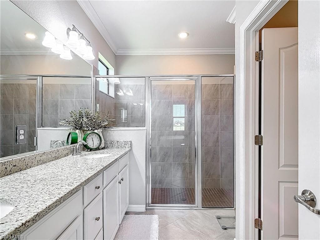 Bathroom with an enclosed shower, vanity, and crown molding