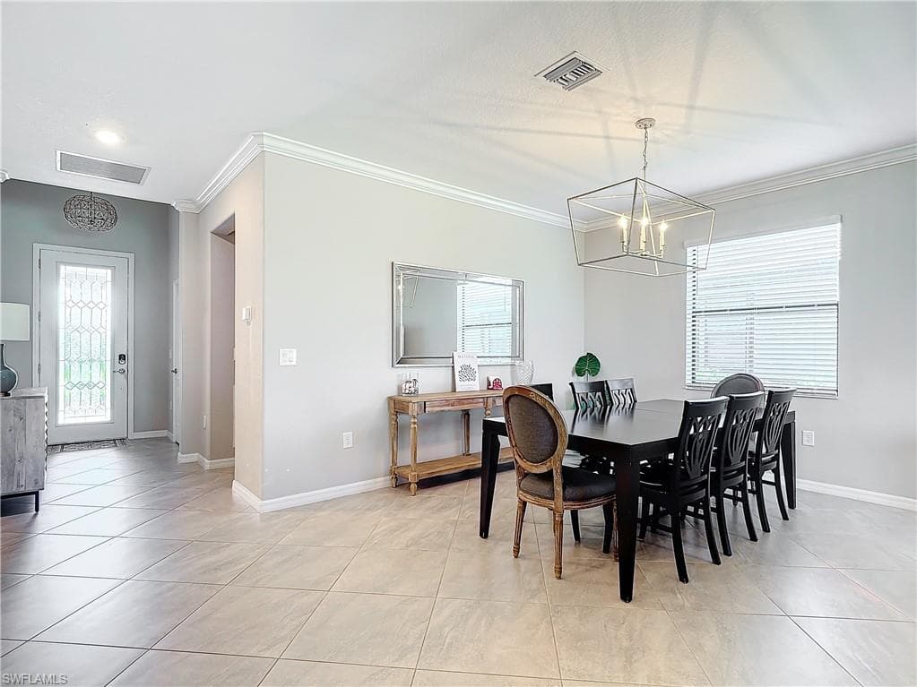 Tiled dining area with an inviting chandelier and crown molding