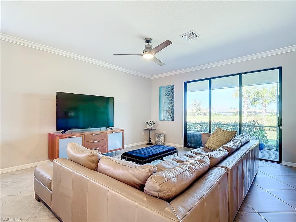 Tiled living room featuring ceiling fan and crown molding
