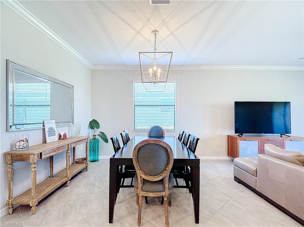 Tiled dining area featuring ornamental molding and a chandelier