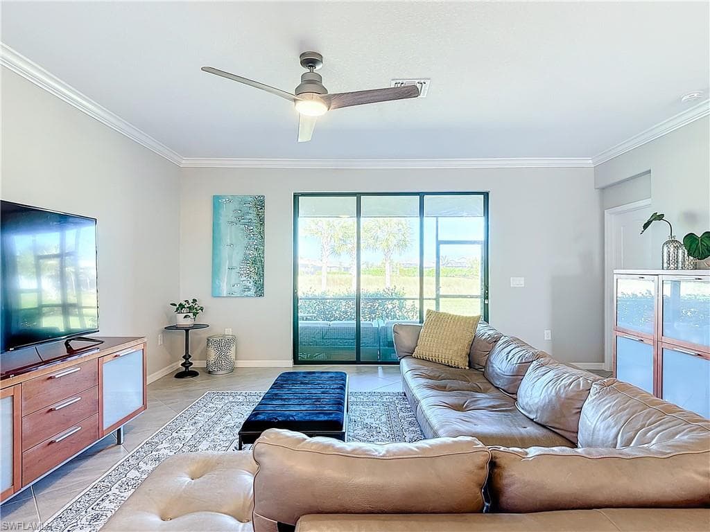 Tiled living room with ceiling fan and ornamental molding