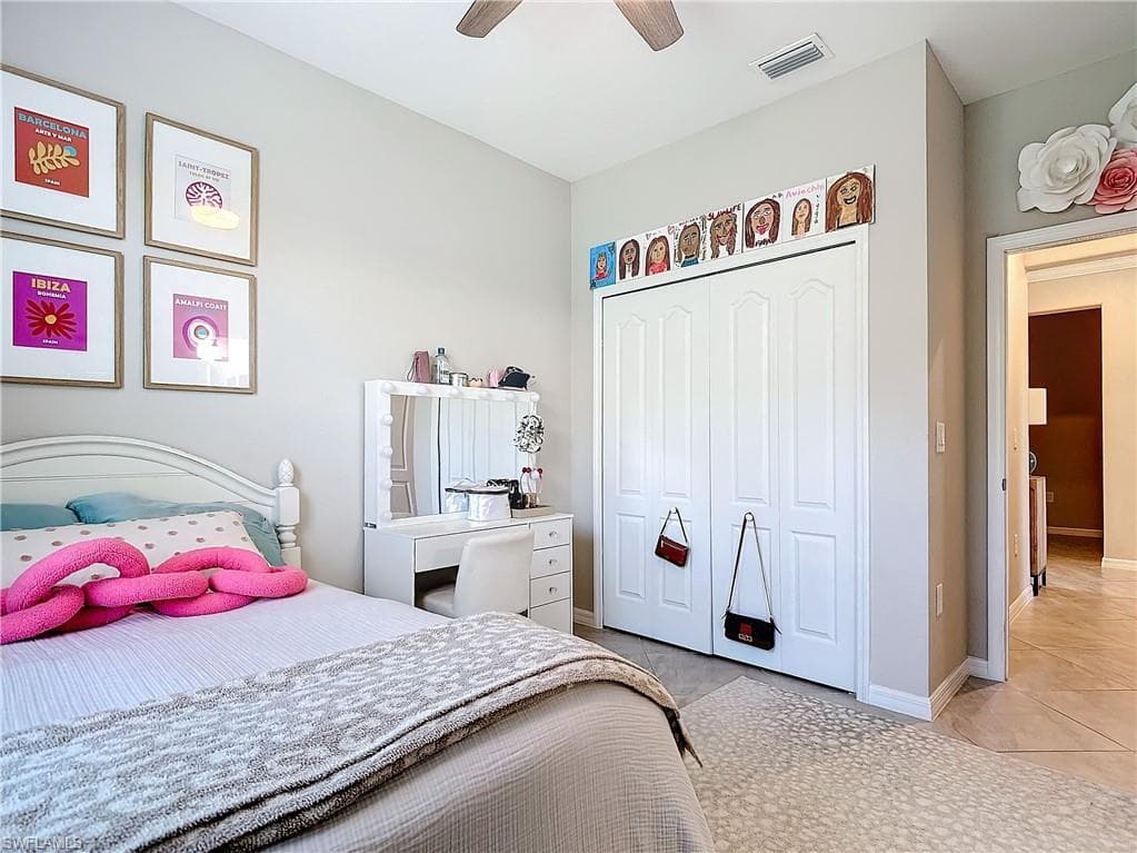 Tiled bedroom with ceiling fan and a closet