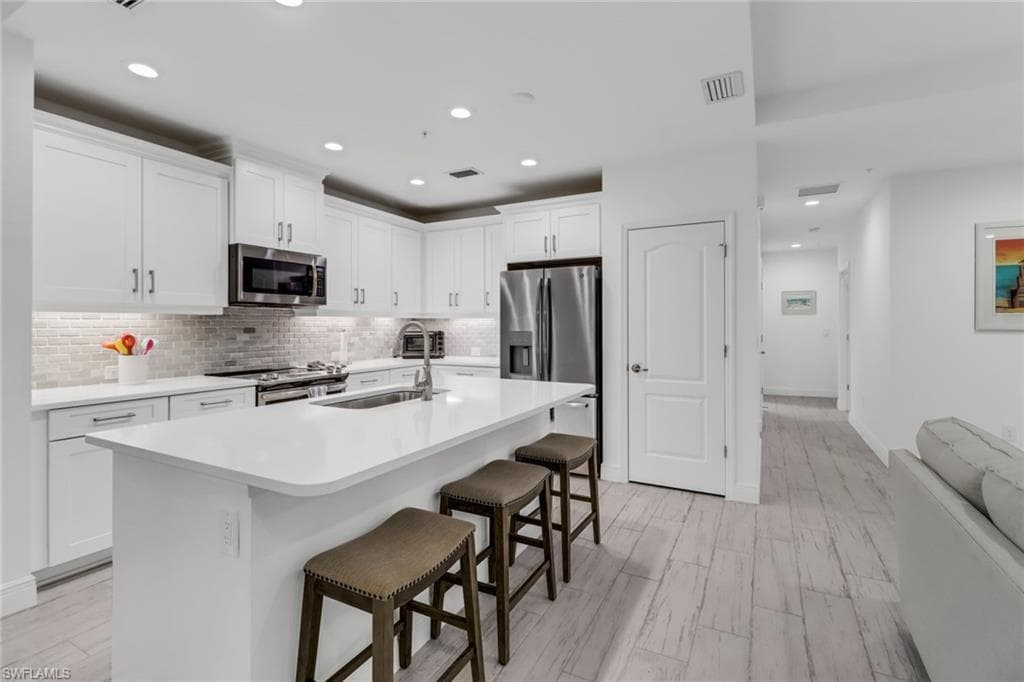 Kitchen featuring white cabinets, sink, a kitchen bar, and stainless steel appliances