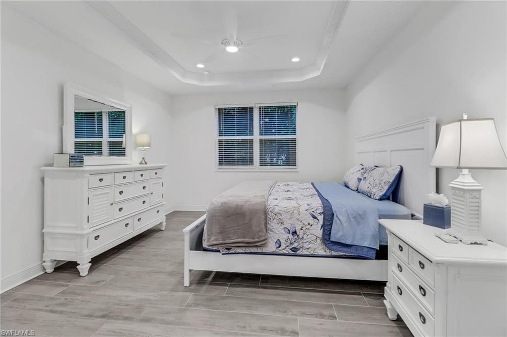 Master Bedroom with light hardwood / wood-style floors, a tray ceiling, and ceiling fan