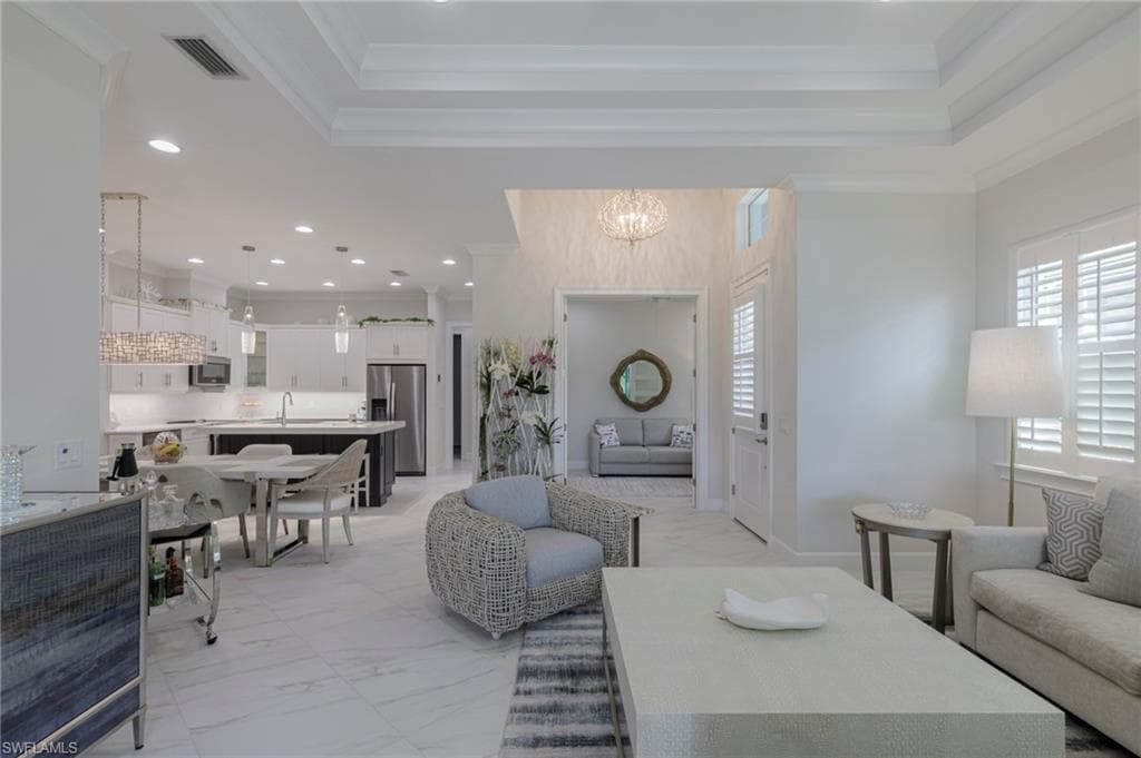 Living room with a notable chandelier, ornamental molding, and sink